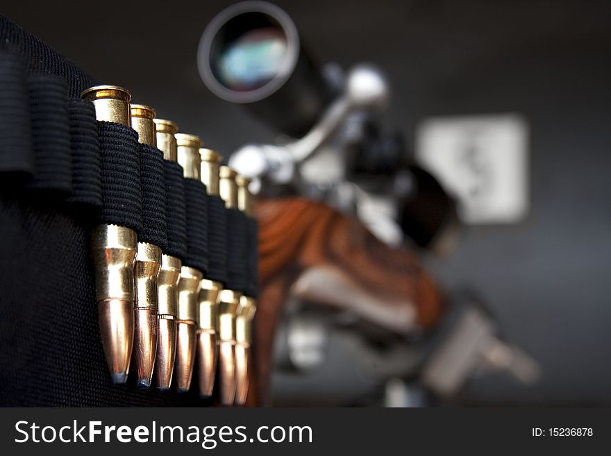 Closeup perspective shot of bullets mounted on gun stock with telescope, selective focus on ammunition. Closeup perspective shot of bullets mounted on gun stock with telescope, selective focus on ammunition