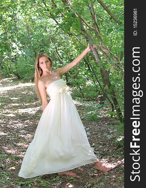 Blond girl in white long dress in the summer forest. Blond girl in white long dress in the summer forest