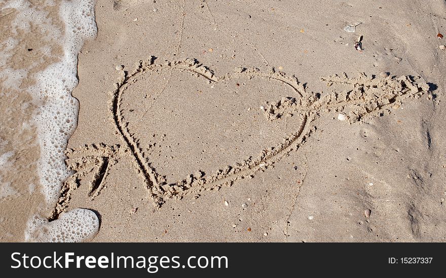 Cupid heart with an arrow in the sand