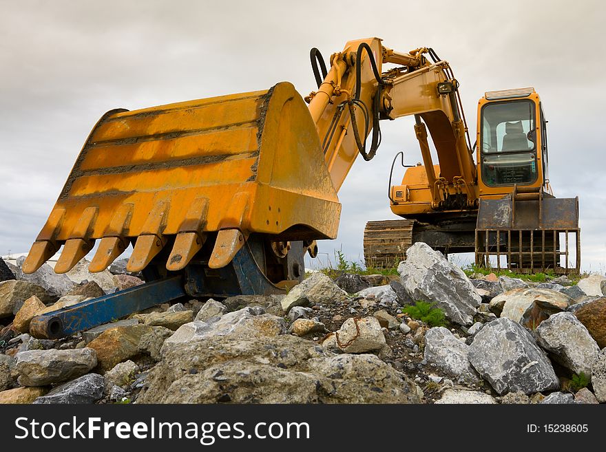 Yellow excavator on top of big heap of stones, close up. Yellow excavator on top of big heap of stones, close up