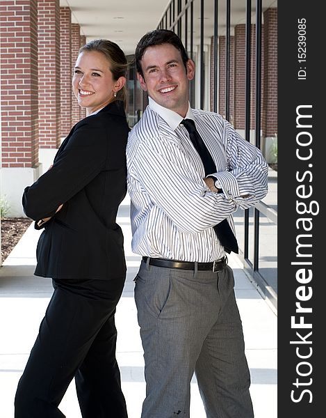 Two business people posing in front of an office building. Two business people posing in front of an office building
