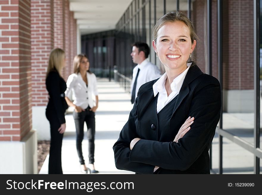 Attractive businesswoman with arms crossed and smiling with team behind