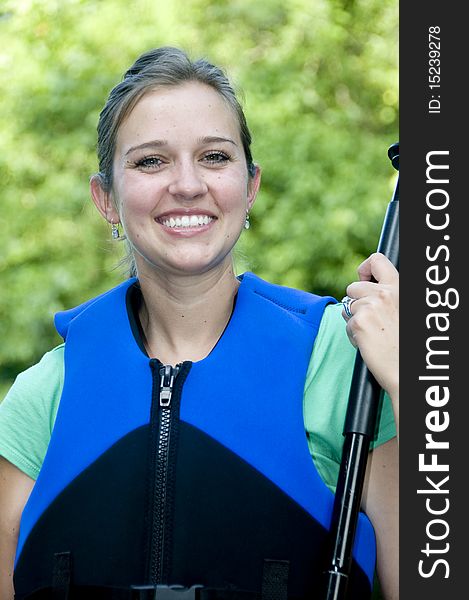 Outdoorsy active female wearing a life jacket and holding a paddle. Outdoorsy active female wearing a life jacket and holding a paddle