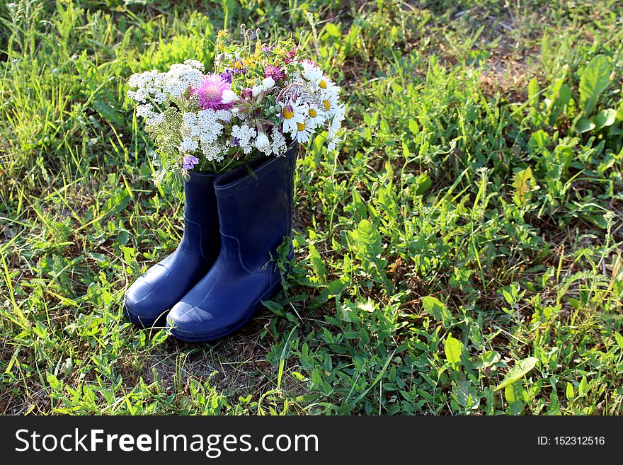 A bouquet of spring wild flowers standing in a rubber boot