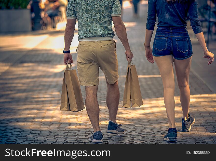 Men and women walk down the street with shopping bags