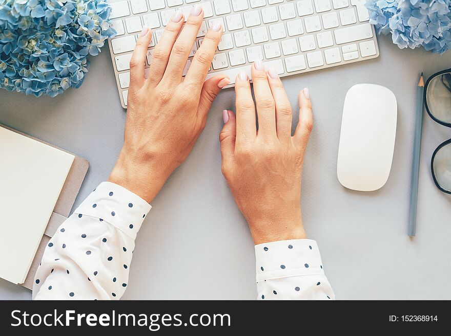 Op view of hands in a polka-dot shirt typing on a computer keyboard