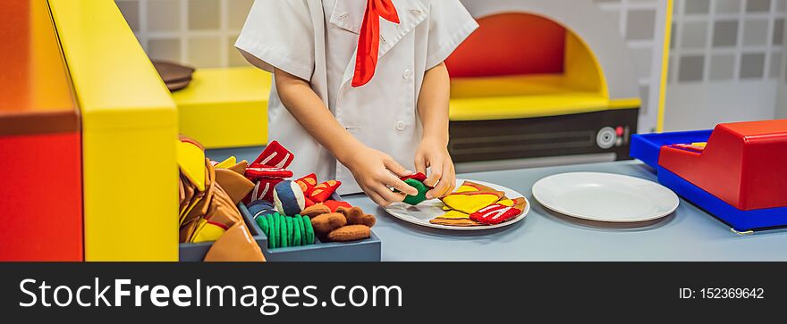 The boy plays in the toy kitchen, cooks a pizza. BANNER, LONG FORMAT