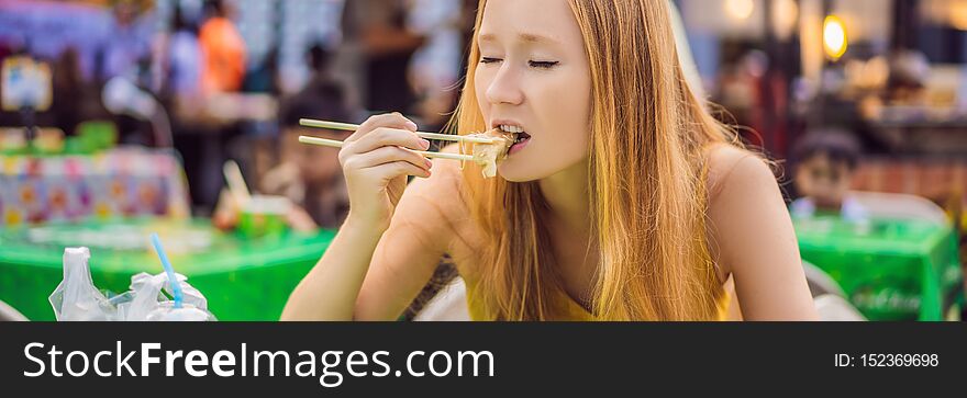 Happy cute gilr eating street food and looking enjoyable in a traditional small fair BANNER, LONG FORMAT