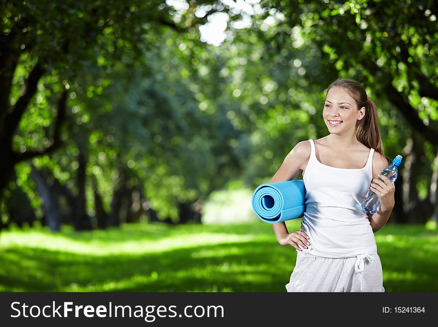Young girl with a bottle of water and gymnastic mat. Young girl with a bottle of water and gymnastic mat