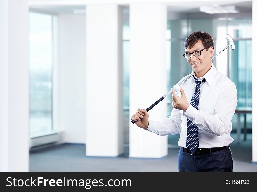 Business man with a golf club in office. Business man with a golf club in office