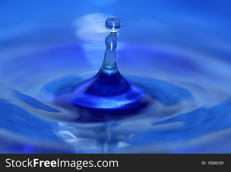 A blue water droplet splashing