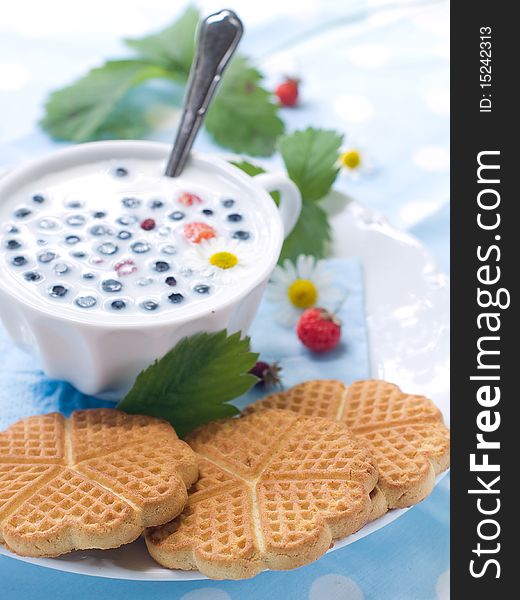 Cup of milk with cookies and berries for breakfast