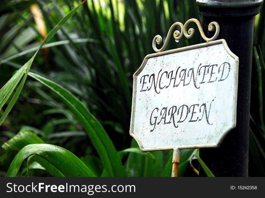A small metal sign in a leafy garden. A small metal sign in a leafy garden