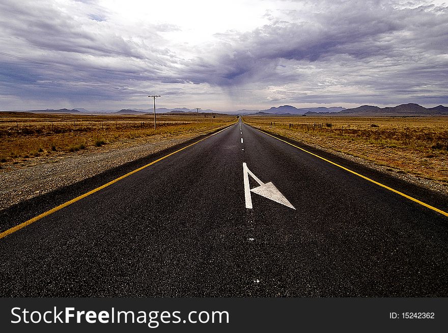 A deserted road leading towards a mountain range. A deserted road leading towards a mountain range