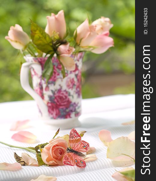 Rose and butterfly with roses in tea mug on background