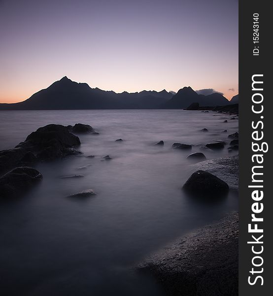 The ky goes purple as the sun sets behind the black cuillin ridge on the isle of skye, scotland. The ky goes purple as the sun sets behind the black cuillin ridge on the isle of skye, scotland.