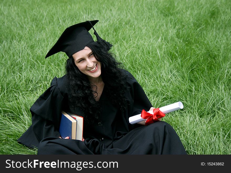 Happy bachelor with diploma on green lawn