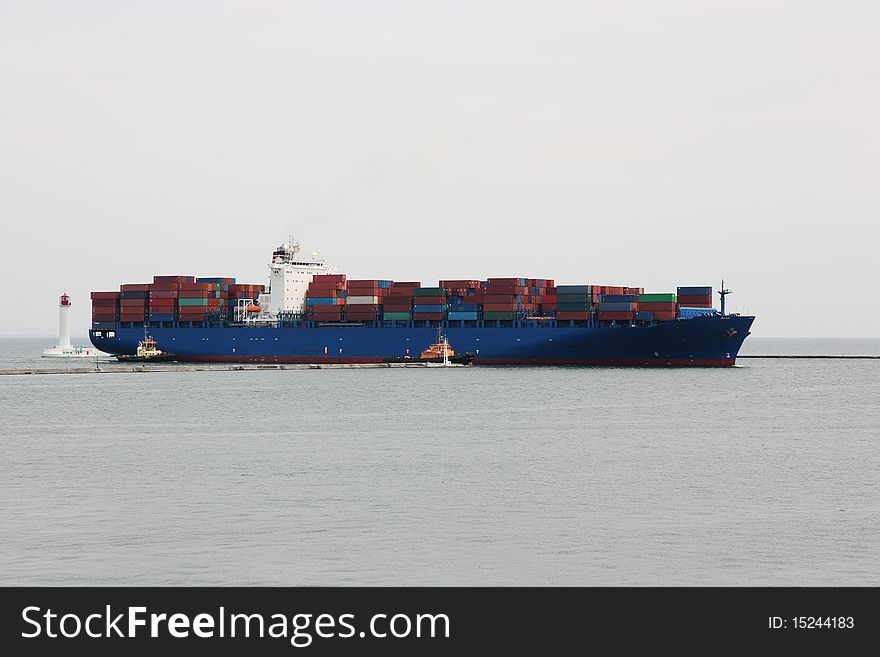 Tugboats pulling a container vessel in sea port area