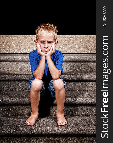 A young boy sitting on concrete steps