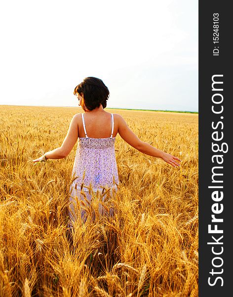 Young beautiful girl walking in the cornfield