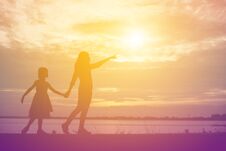A Silhouette Of A Happy Young Girl Child The Arms Of His Loving Mother For A Hug, In Front Of The Sunset In The Sky On A Summer Royalty Free Stock Photography