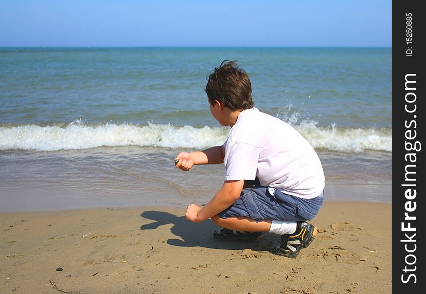 Boy skipping rocks at a beach on a sunny summer day.