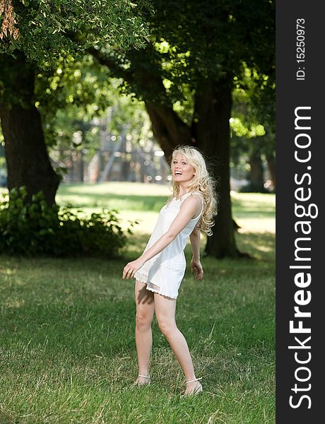 Young blond is dancing in her sundress under shadily trees in the park. Young blond is dancing in her sundress under shadily trees in the park