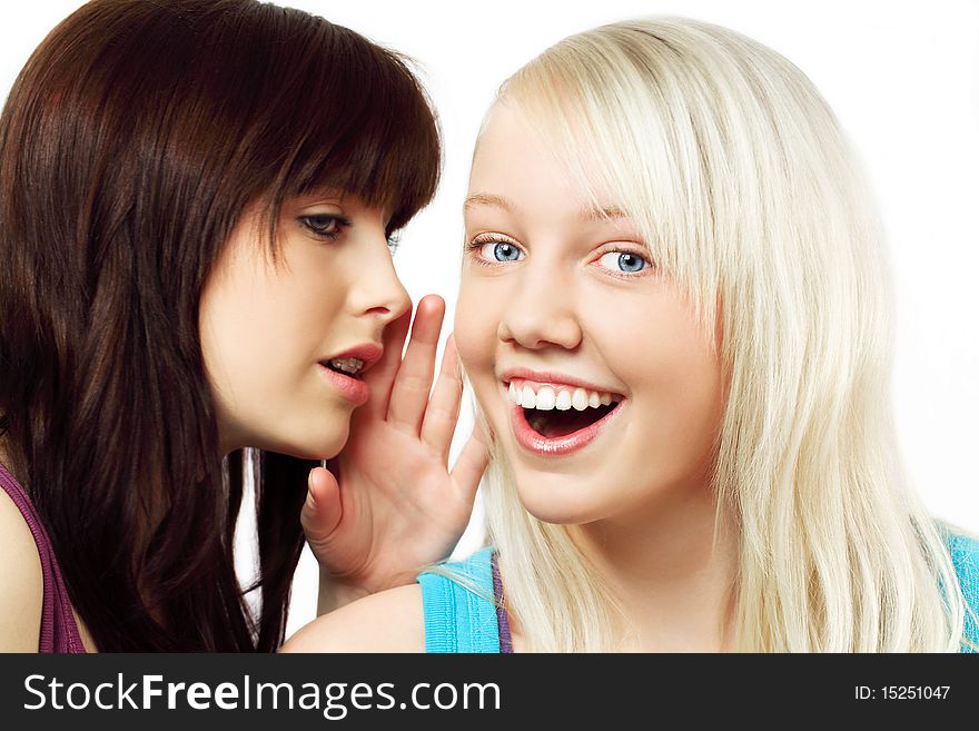 Two cute girls,one is whispering and the other is surprised about what she is hearing,isolated on white. Two cute girls,one is whispering and the other is surprised about what she is hearing,isolated on white