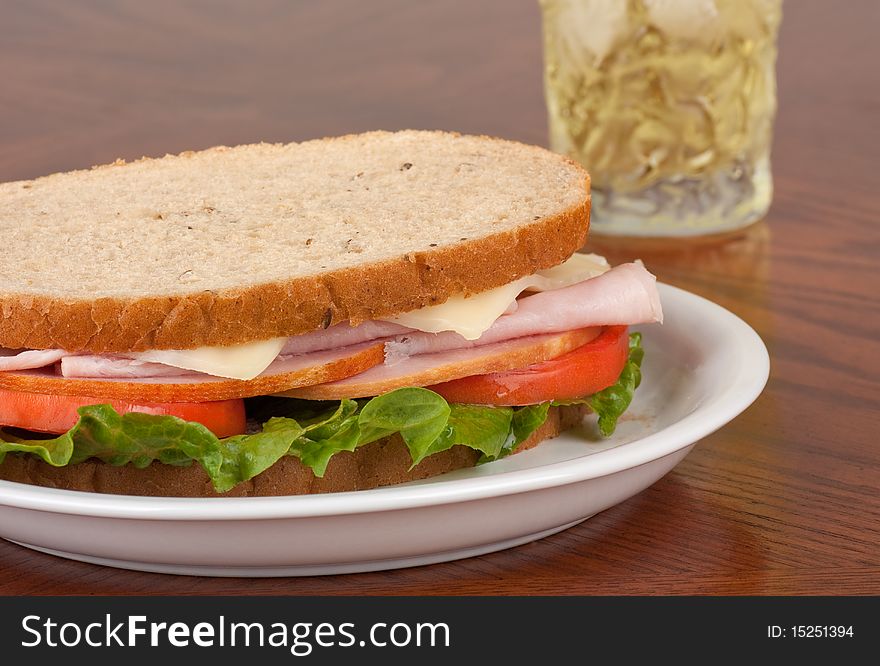 Ham and swiss cheese sandwich with lettuce and tomato on rye bread. Ham and swiss cheese sandwich with lettuce and tomato on rye bread