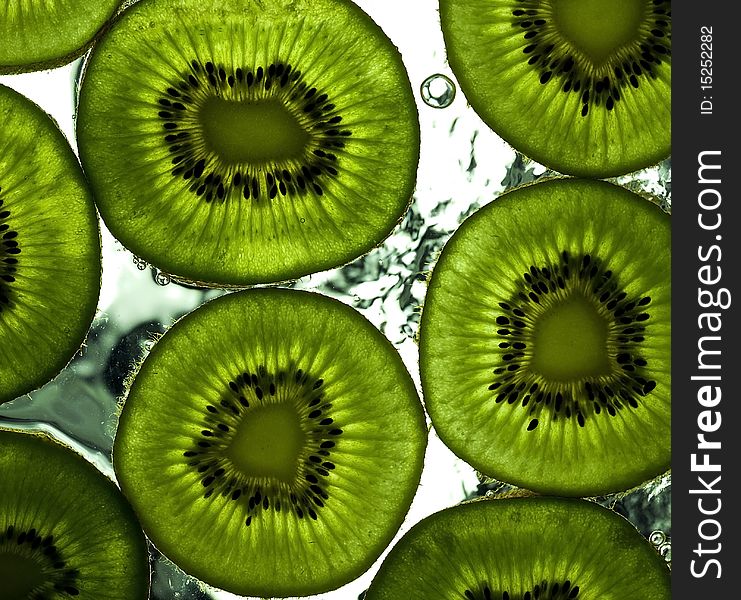 Sliced kiwi on the glass with flowing water. Sliced kiwi on the glass with flowing water