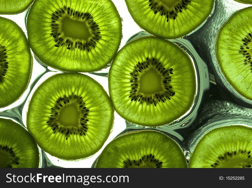 Sliced kiwi on the glass with flowing water. Sliced kiwi on the glass with flowing water