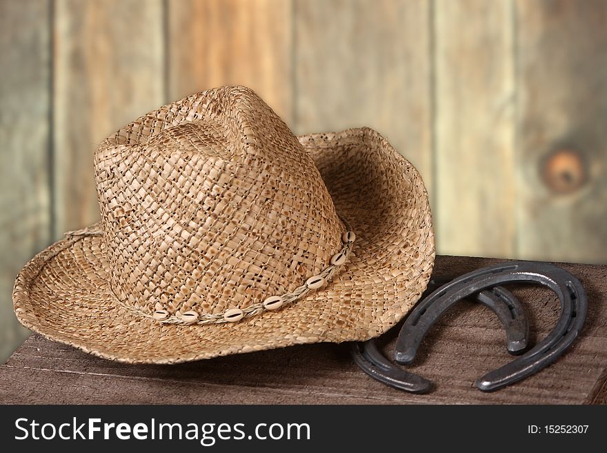 Old west scene with a cowboy hat and two horseshoes set against a wooden fence backdrop. Old west scene with a cowboy hat and two horseshoes set against a wooden fence backdrop.