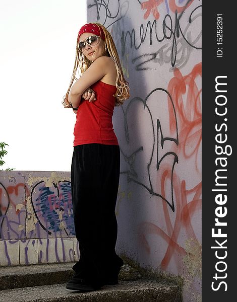 Teenage rapper girl standing outdoors at graffiti sprayed wall. Teenage rapper girl standing outdoors at graffiti sprayed wall