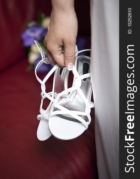 White wedding sandals in bride's hand. White wedding sandals in bride's hand