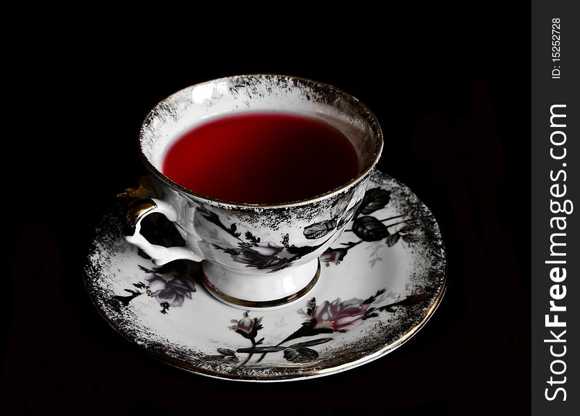 Porcelain cup of red tea in black background
