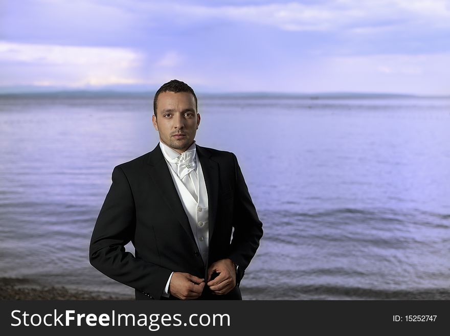 Young groom in wedding suit by the sea