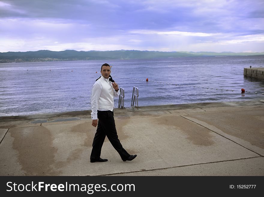 Young groom in wedding suit by the sea