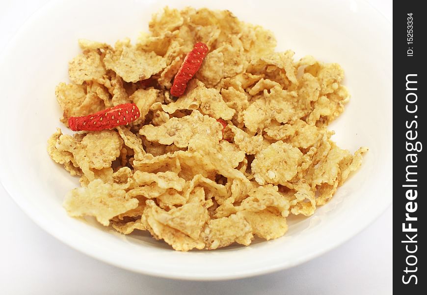 Corn flakes (cereal) with dried strawberry slices without milk in a bowl