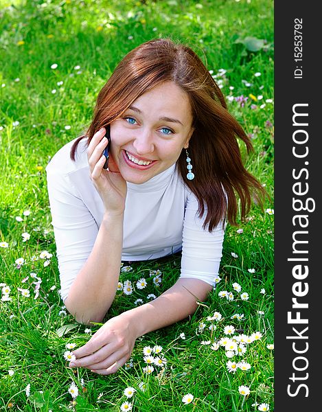 The girl with the phone on the grass, vertical