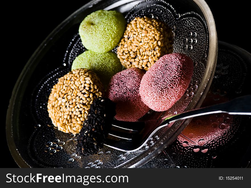 Assorted sweets on plate on black background