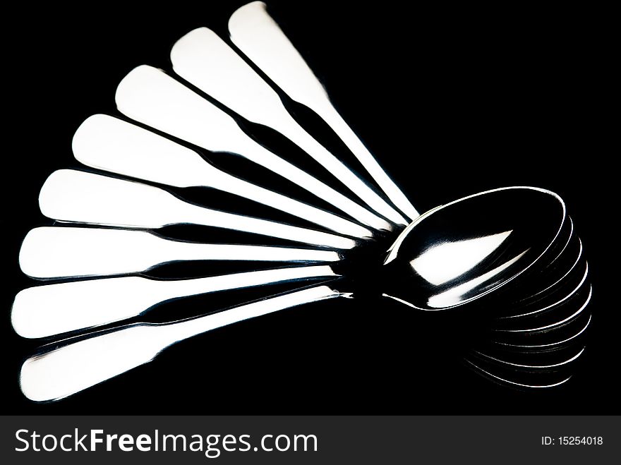 Teaspoons arranged in fan shape on black background
