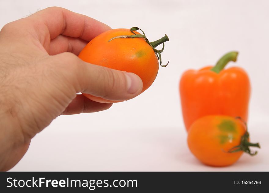 orange tomato and paprika in mans hand