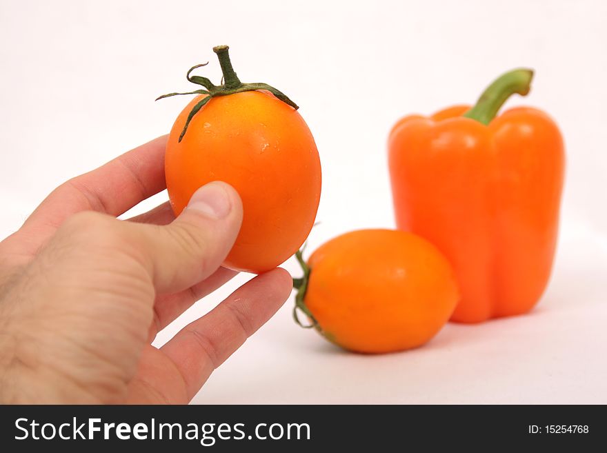 Orange tomato and paprika in mans hand