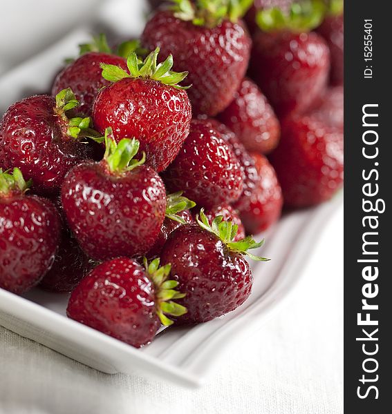 Luscious, fresh strawberries on a modern white platter. Shallow depth of field.