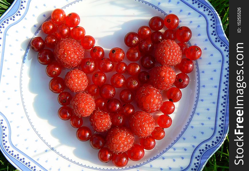 Red fruits heart on the plate. Red fruits heart on the plate