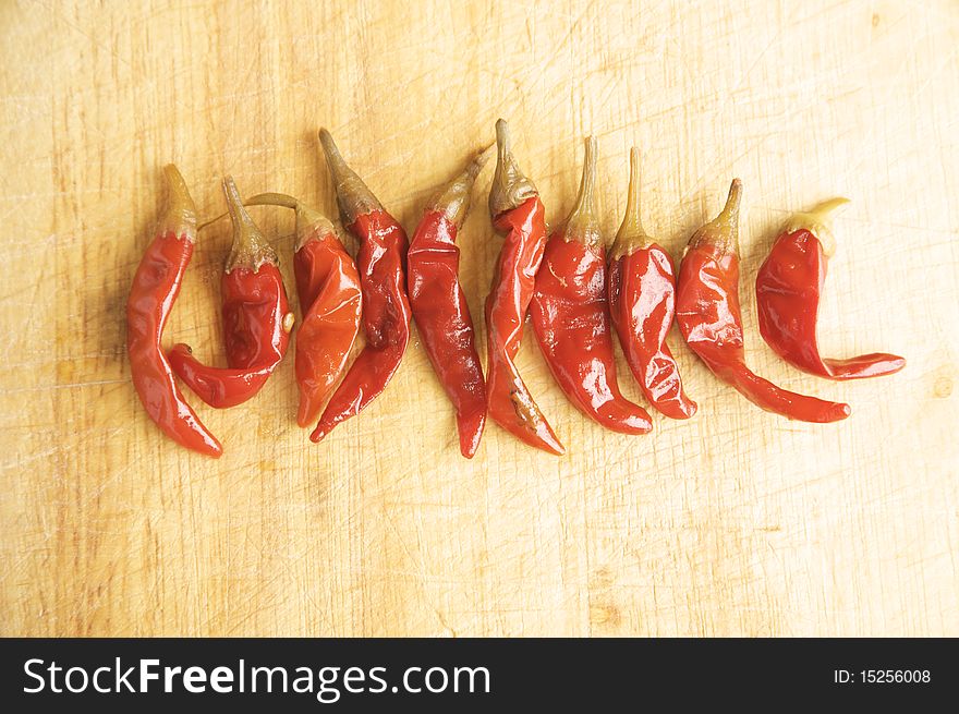 Red Hot Chillies on a wooden kitchen table, lit with a large light source from the right.