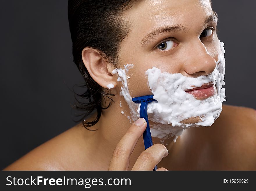handsome young man shaving. handsome young man shaving