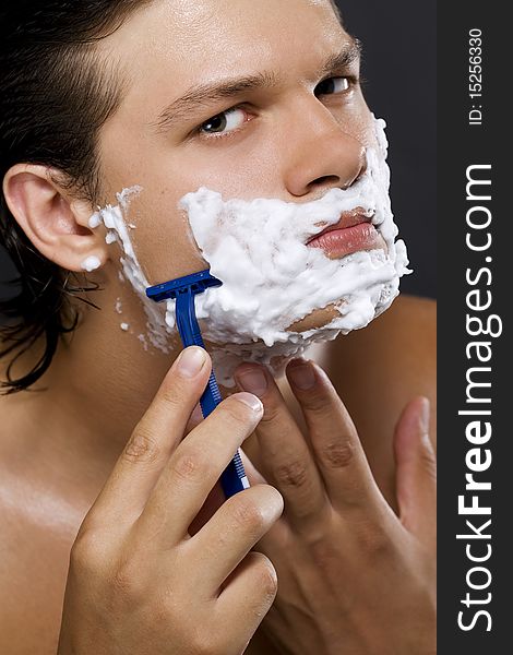 handsome young man shaving. handsome young man shaving