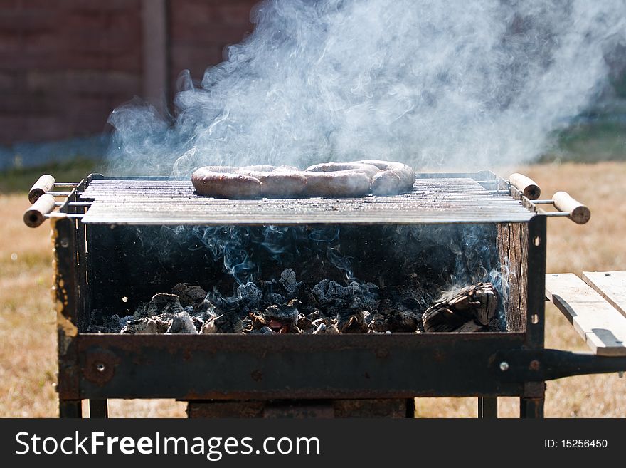 An old rusty dirty grill with sausages on the grid and hot burning coal below. An old rusty dirty grill with sausages on the grid and hot burning coal below