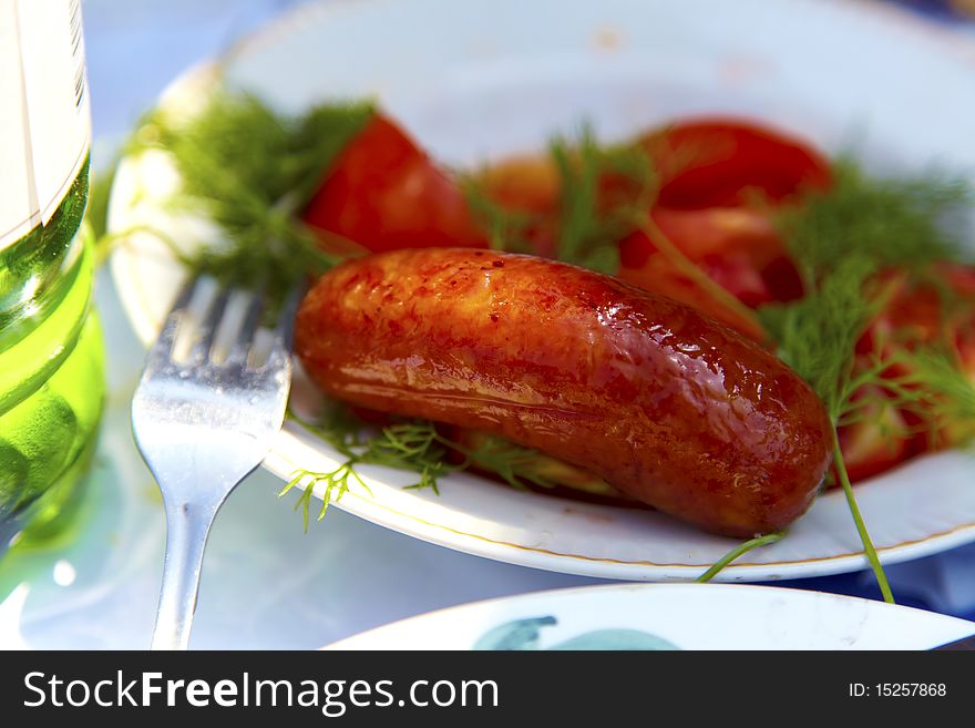 Grilled sausages on a plate with parsley and dill